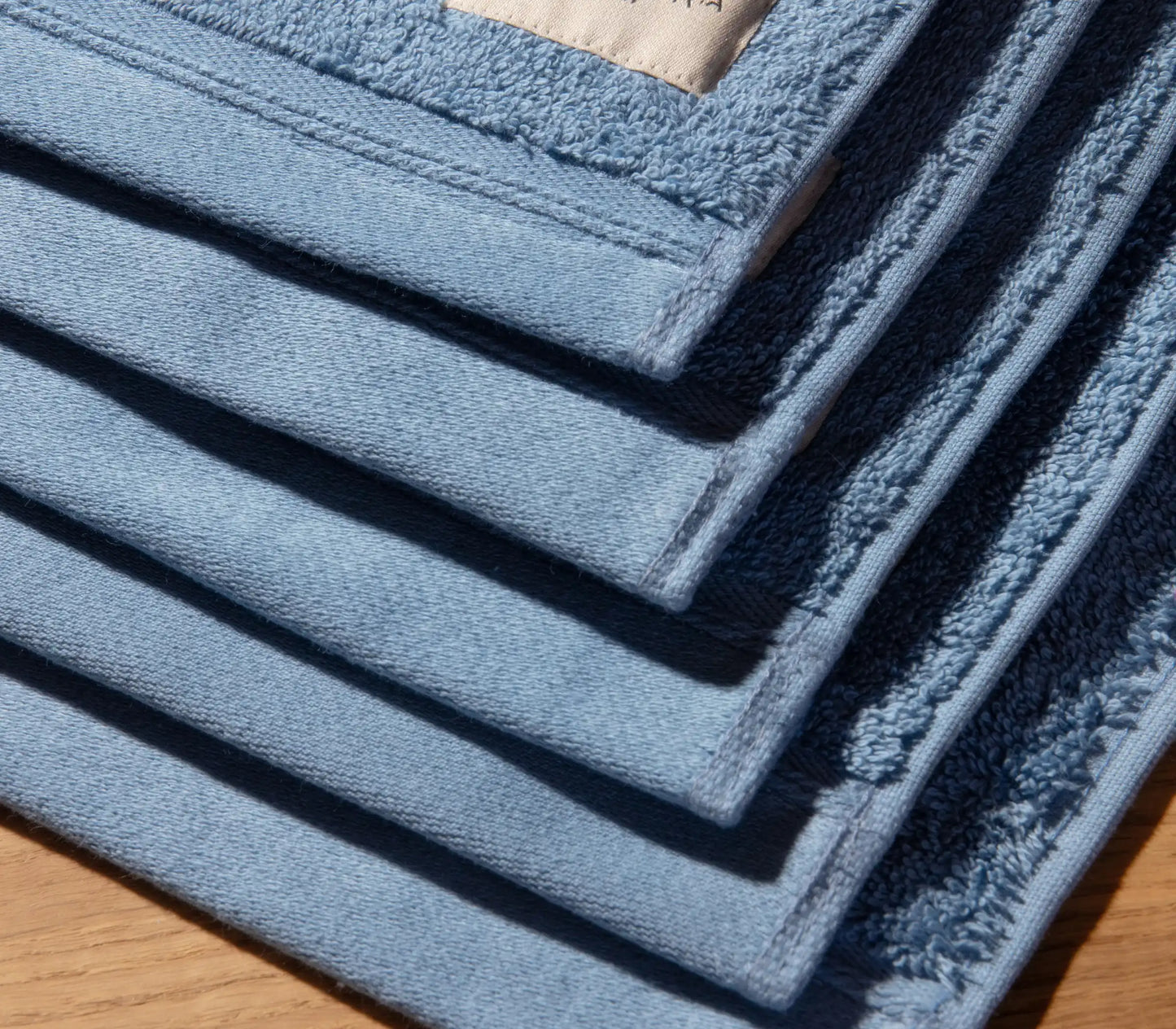 Stack of blue bath mats on a wooden floor