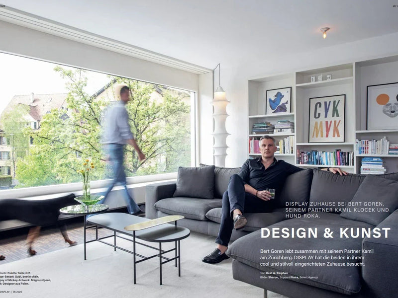 two people in a room, one with a dog and the other sitting on the couch