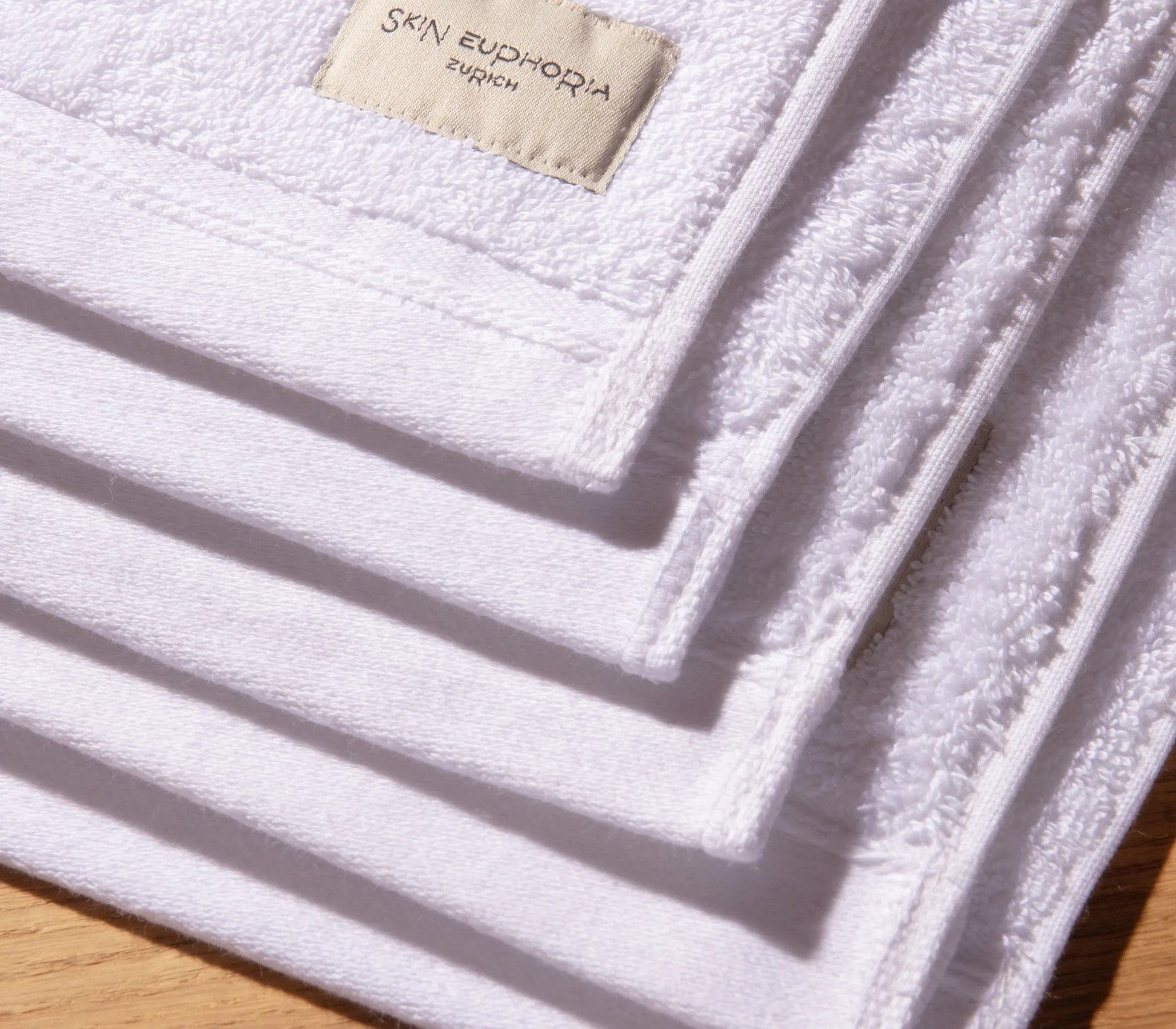 White towel with 'Skin Euphoria' label on a wooden surface