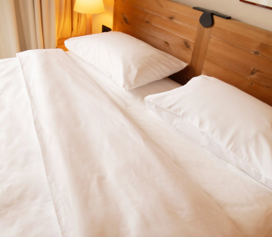 Neatly made bed with white bedding in a bedroom setting.