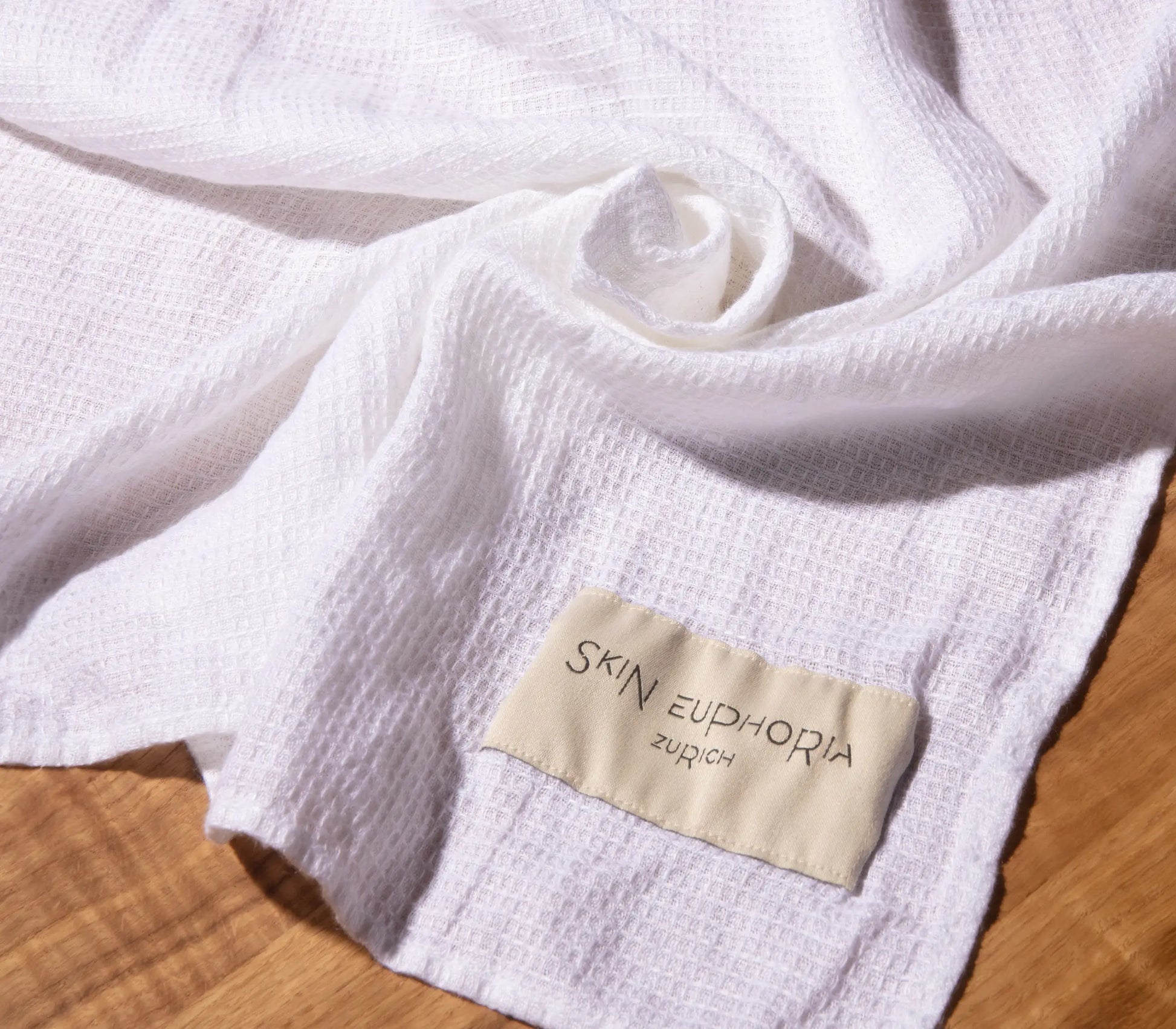White fabric with a 'Skin Euphoria Zurich' label on a wooden surface
