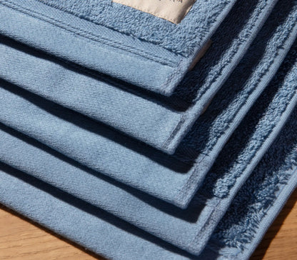 Stack of blue bath mats on a wooden floor