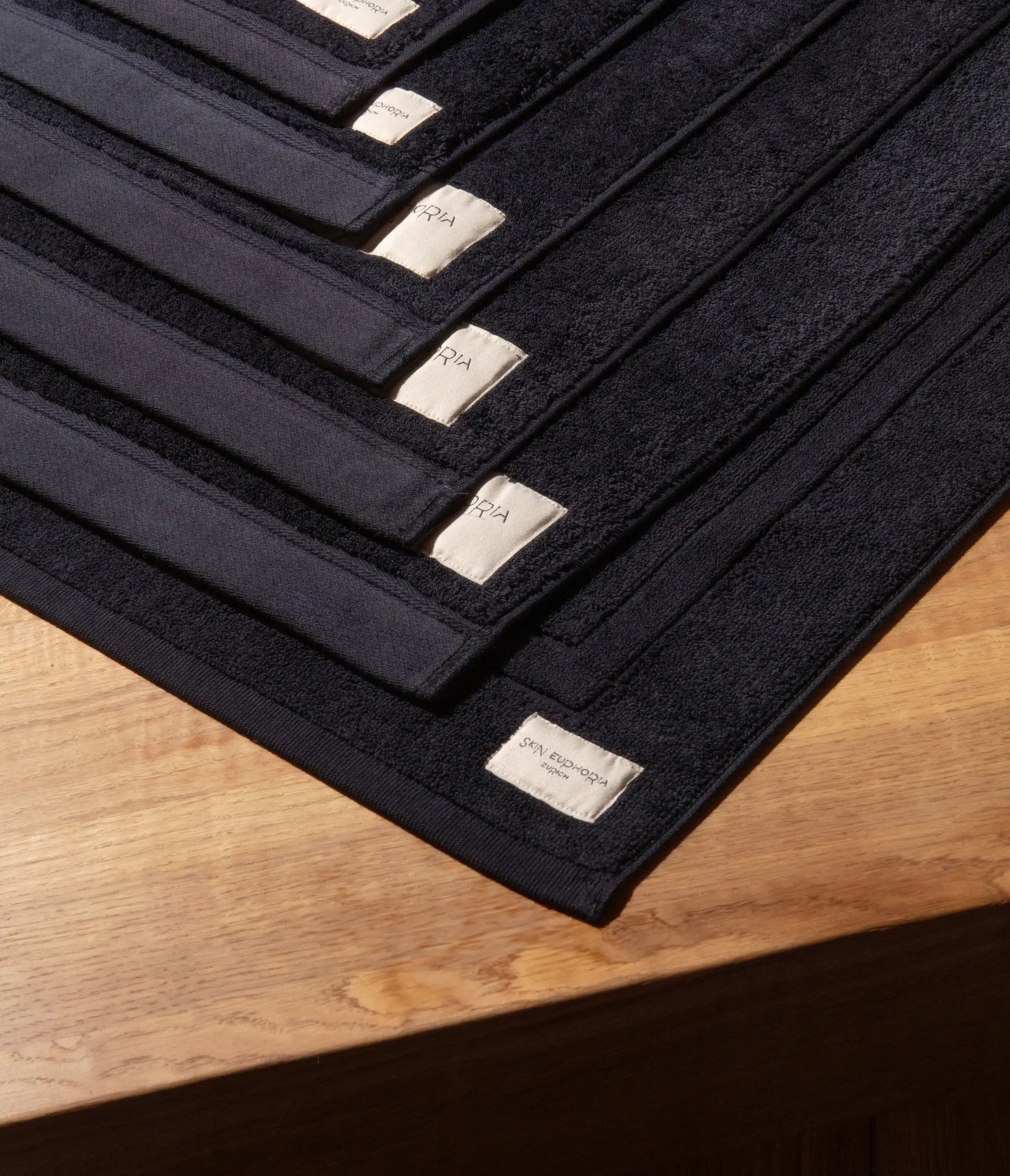 Set of black towels with gold labels on a wooden surface