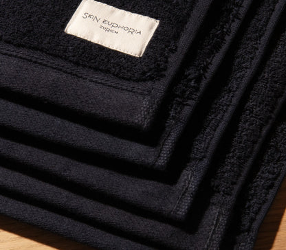 Black towel with 'Skin Euphoria Zurich' label on a wooden surface