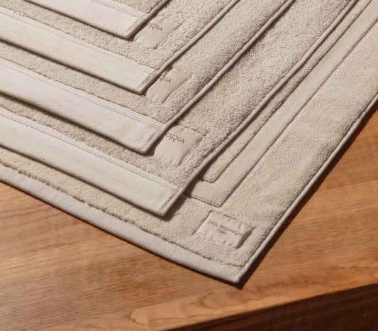 Beige bath mat with textured pattern on a wooden floor