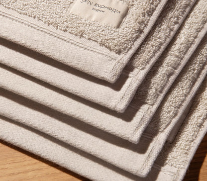 Stack of beige towels with 'Skin Euphoria' branding on a wooden surface