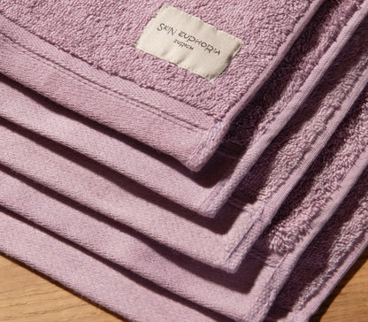 Stack of pink towels with a brand label on a wooden surface