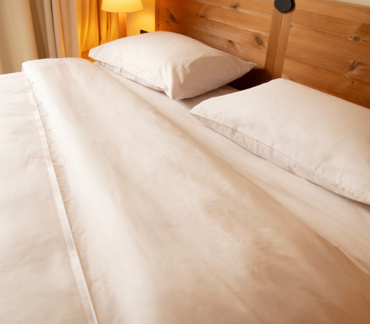 Neatly made bed with white bedding and pillows in a bedroom setting.