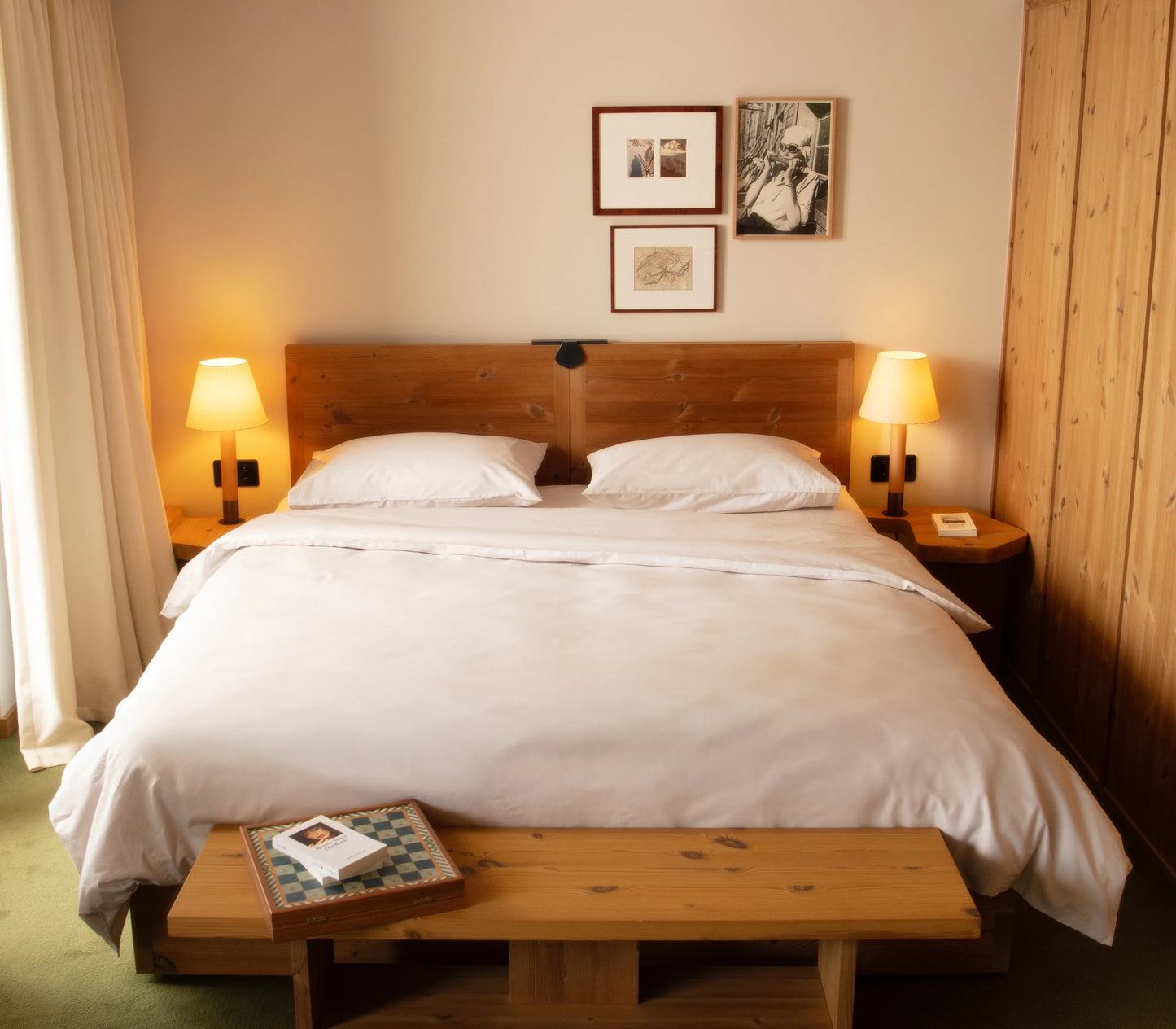 Bedroom with wooden bed and nightstands, lamps, and framed pictures on the wall.