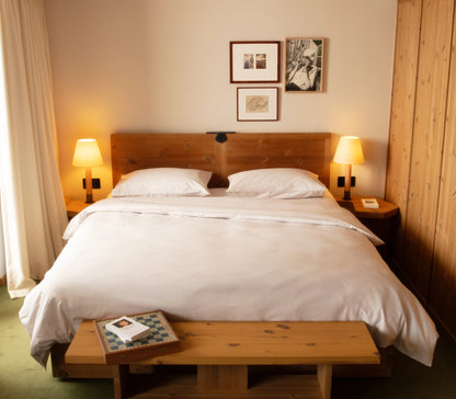 Bedroom with wooden bed and nightstands, lamps, and framed pictures on the wall.