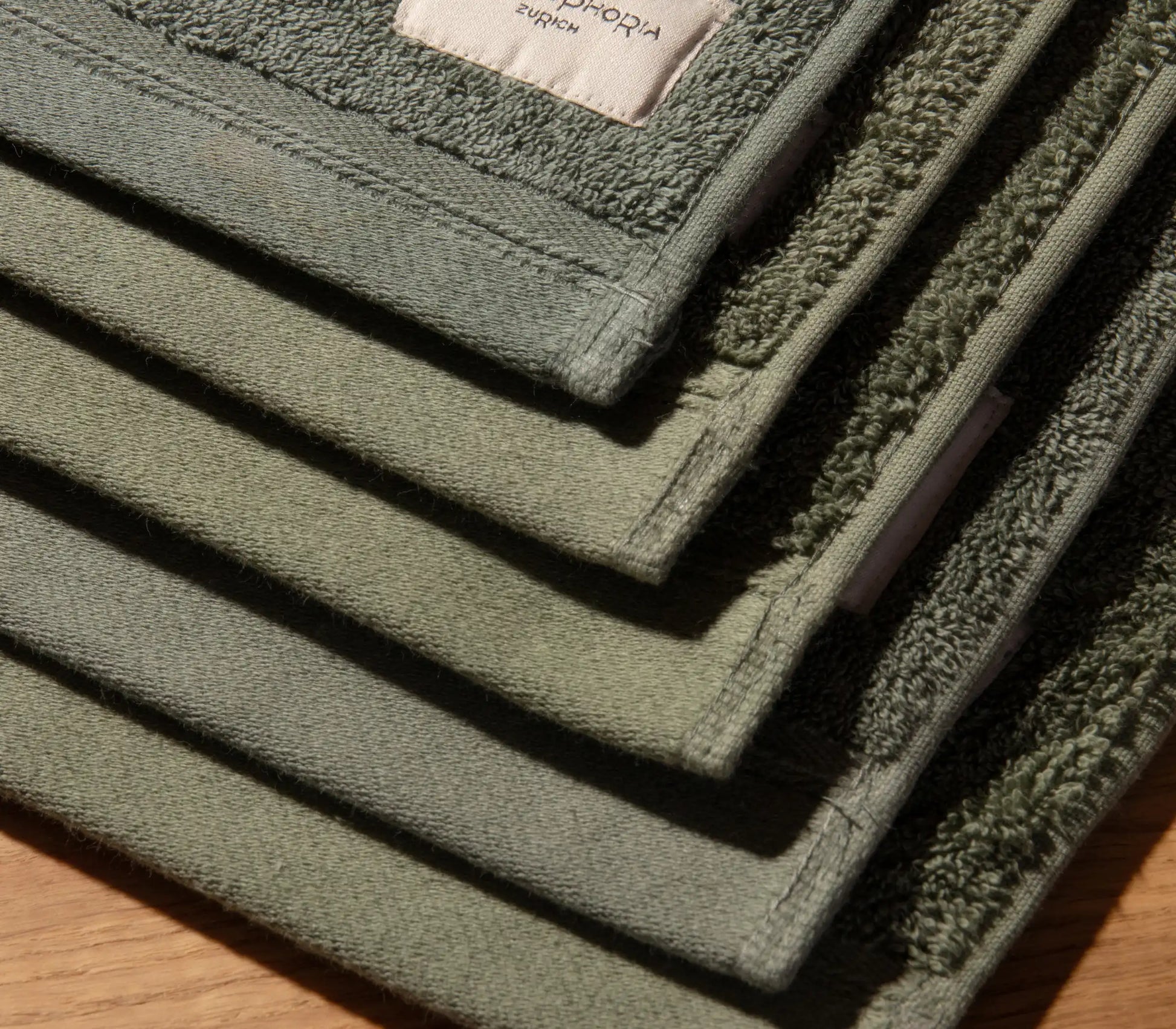 Stack of green bath mats on a wooden surface