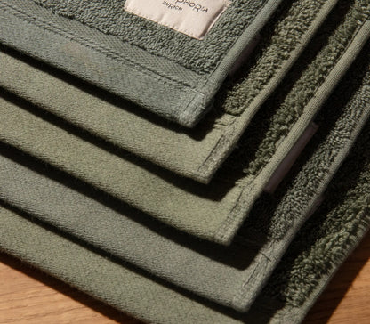 Stack of green bath mats on a wooden surface