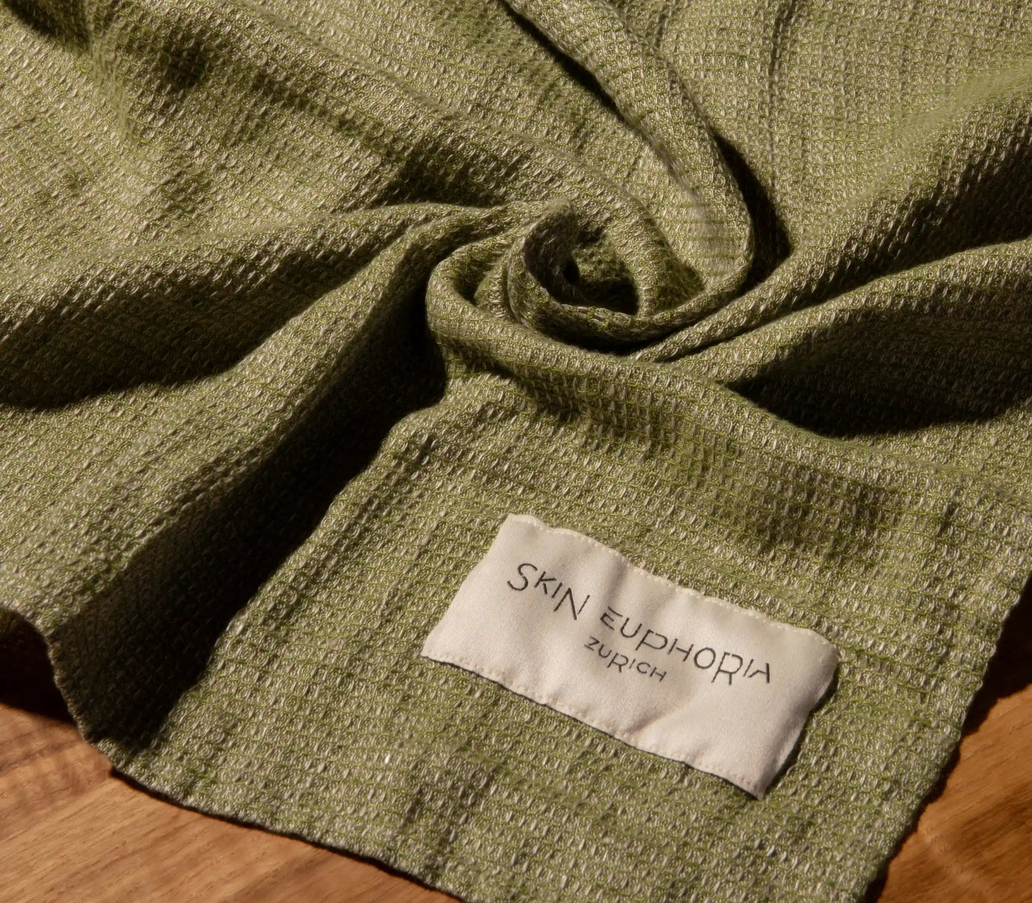 Green fabric with a 'Skin Euphoria Zurich' label on a wooden surface