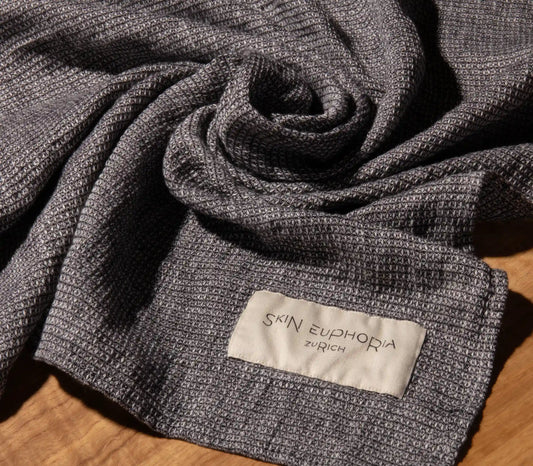 Textured gray fabric with 'Skin Euphoria Zurich' label on a wooden surface