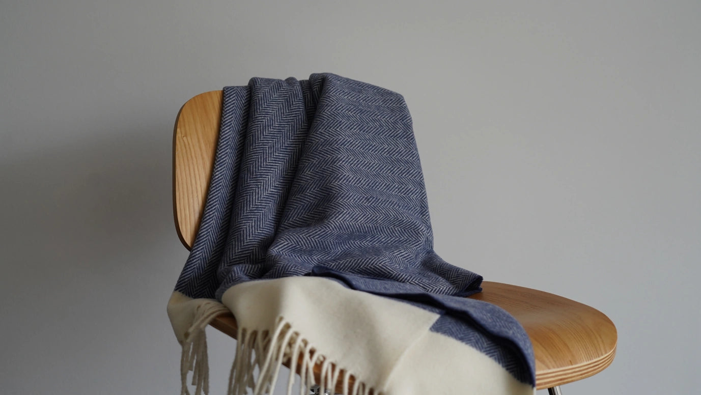 Blue woven blanket draped over a wooden chair with a plain background