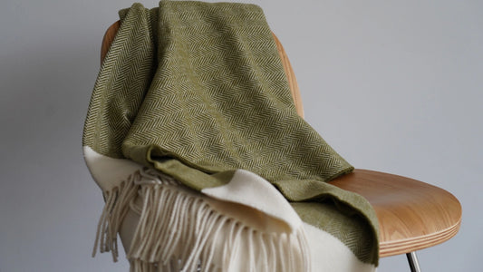 Green blanket draped over a chair with a white and beige fringe